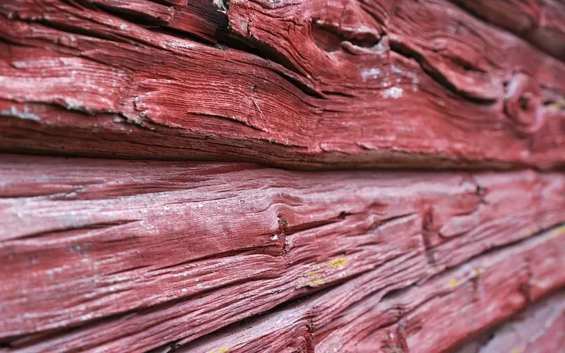 Weathered red-painted exterior boards with deep grain cracks Weathered red-painted exterior boards with deep grain cracks