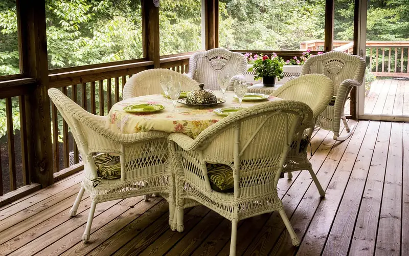 white all-weather wicker chairs and table on a screened porch deck white all-weather wicker chairs and table on a screened porch deck