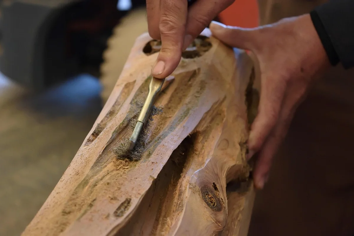 Craftsman's hands carving wood, representing the hands-on skill Maloof-inspired makers practice today