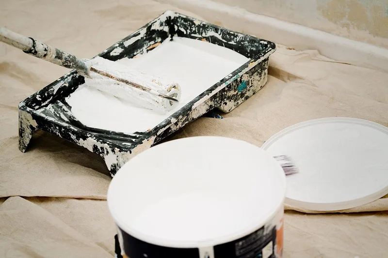 Paint roller, tray, and can of floor paint ready for painting a wood floor
