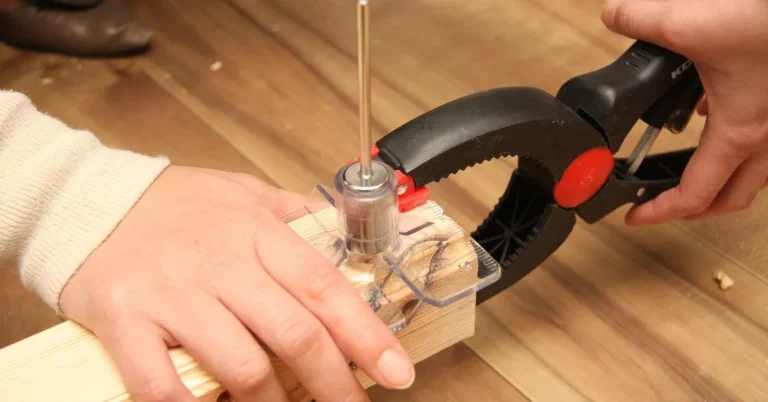 Hand clamping a wood board with a spring clamp during a woodworking project