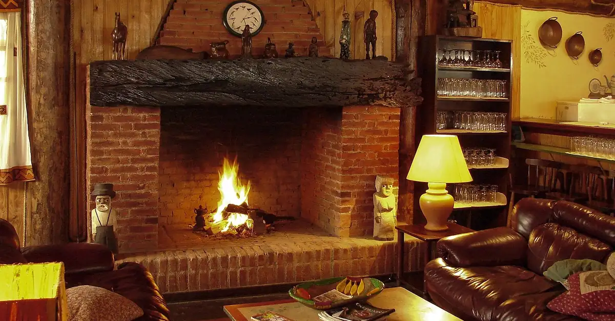 brick fireplace burning firewood in a wood-paneled living room