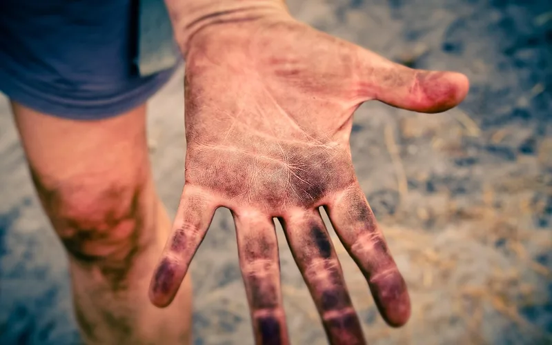 close-up of wood stain pigment soaked into the creases of a hand and fingertips