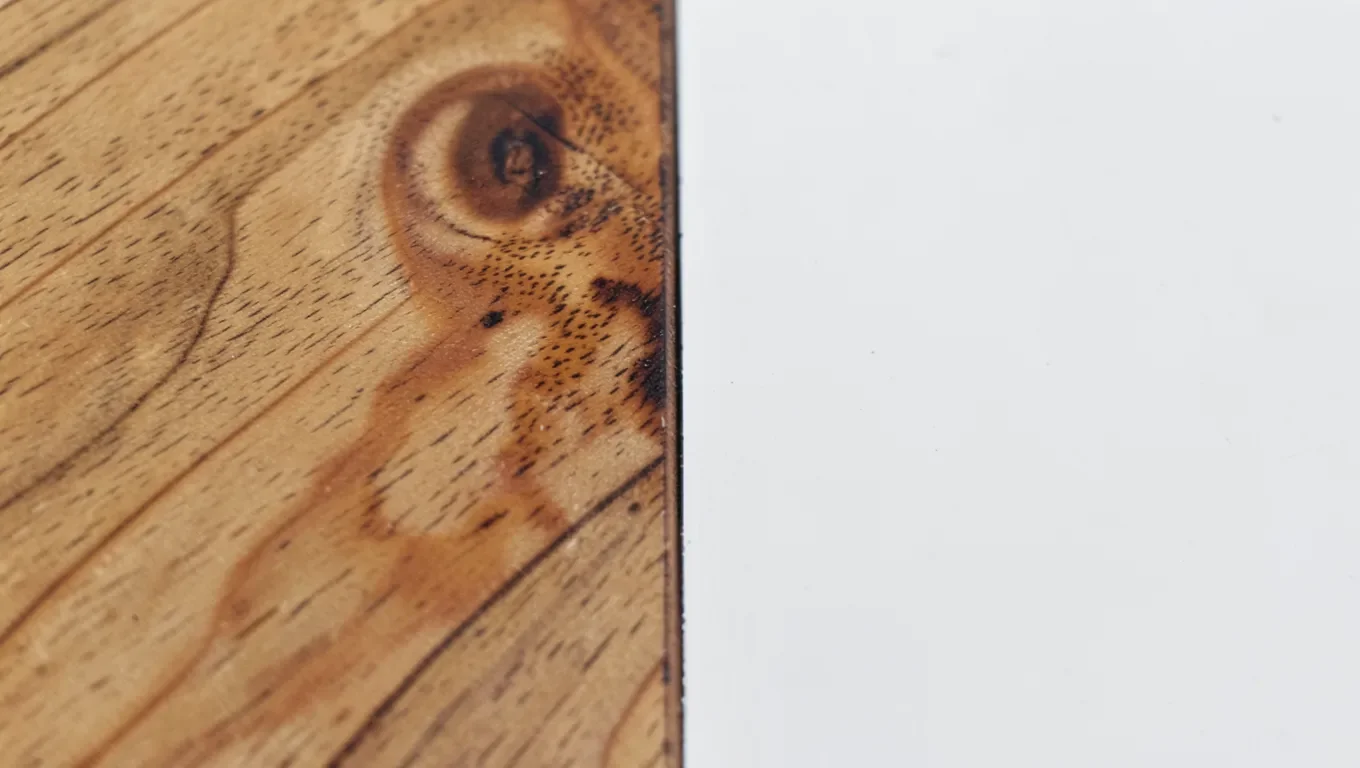 Wood grain visible through stain on the left next to a smooth opaque painted wood surface on the right