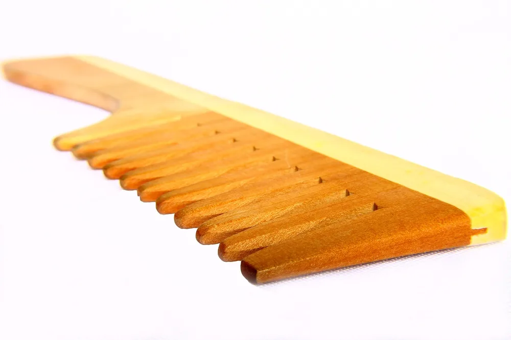 Wooden wide-tooth comb close-up showing smooth polished teeth