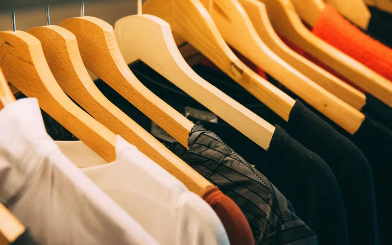 Wool sweaters and jackets on wooden hangers on a closet rod