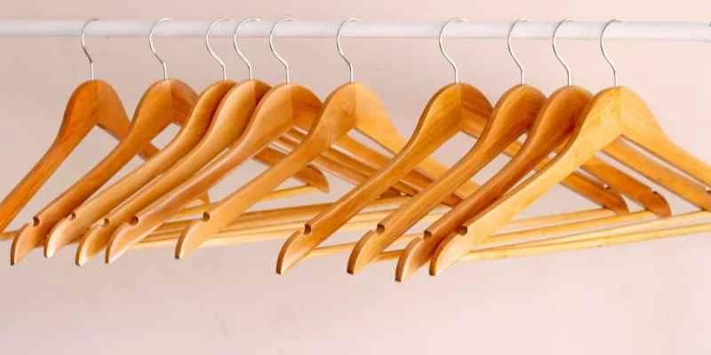 Row of wooden suit hangers on a closet rod