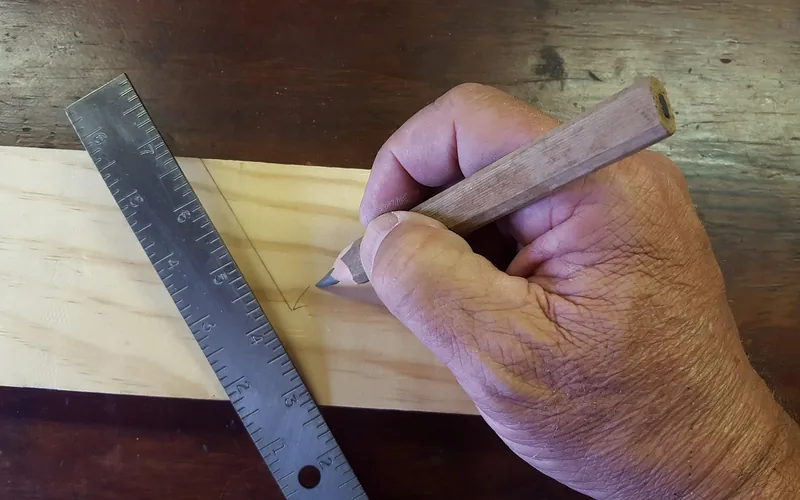 Carpenter marking a measurement on a wood board with a steel ruler and pencil Carpenter marking a measurement on a wood board with a steel ruler and pencil
