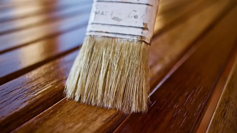 Brush applying a rich dark mahogany oil-based wood stain to a wood board, showing the deep reddish-brown color ZAR 118 produces