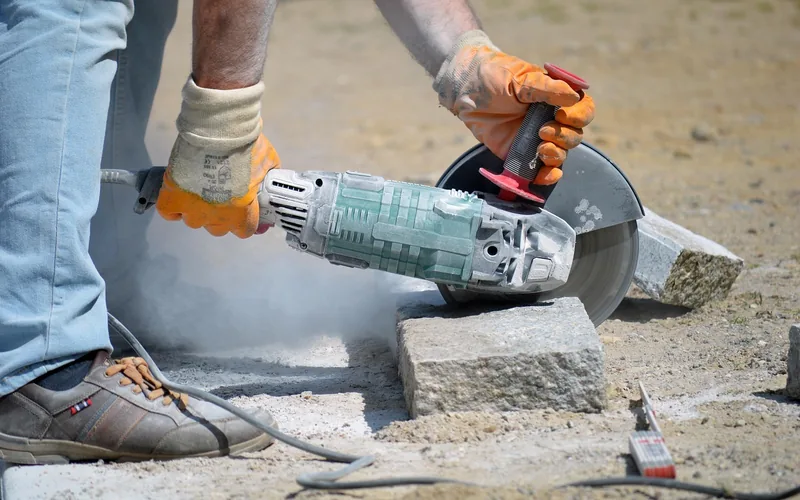 handheld angle grinder cutting through stone with an abrasive cut-off wheel handheld angle grinder cutting through stone with an abrasive cut-off wheel
