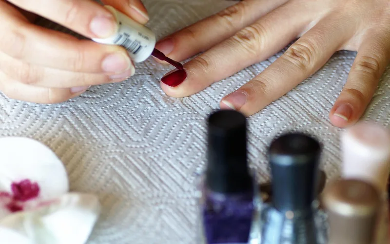 Applying a thin coat of nail polish with a small brush Applying a thin coat of nail polish with a small brush