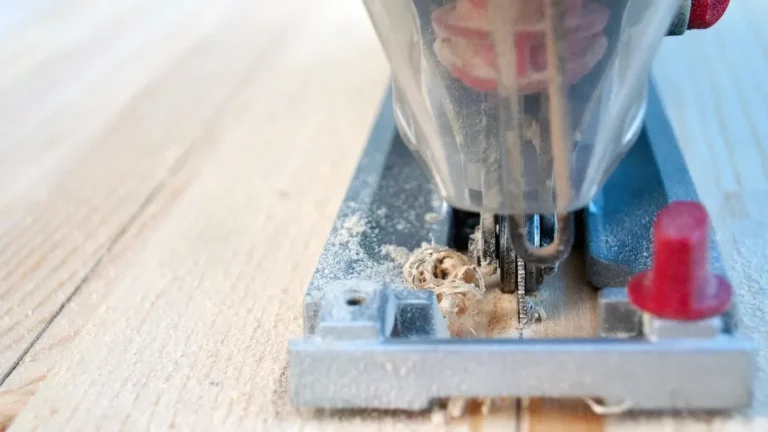 Jigsaw base plate and blade cutting a pine board with fresh sawdust