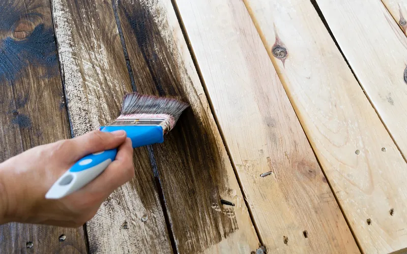 Brushing a dark wood finish along the grain of rough boards Brushing a dark wood finish along the grain of rough boards