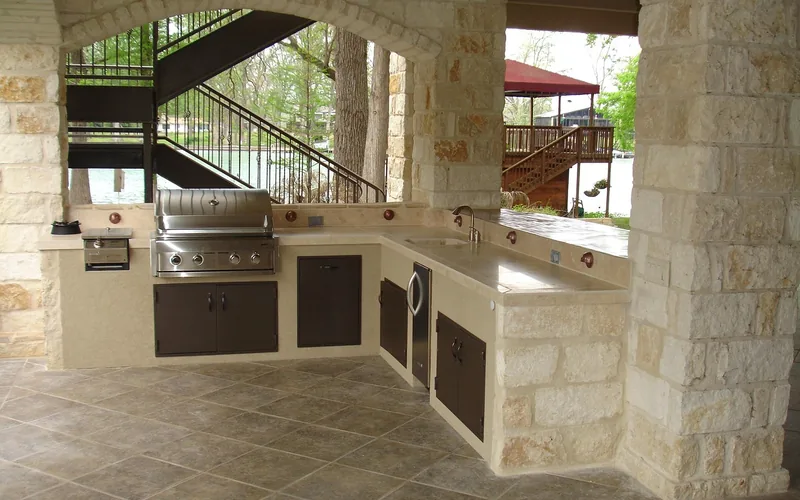 stainless steel built-in grill set into a stone outdoor kitchen counter with cabinet doors below