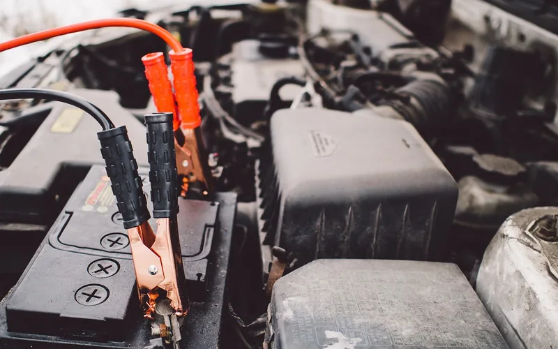 jumper cable clamps attached to a car battery terminal under the hood jumper cable clamps attached to a car battery terminal under the hood