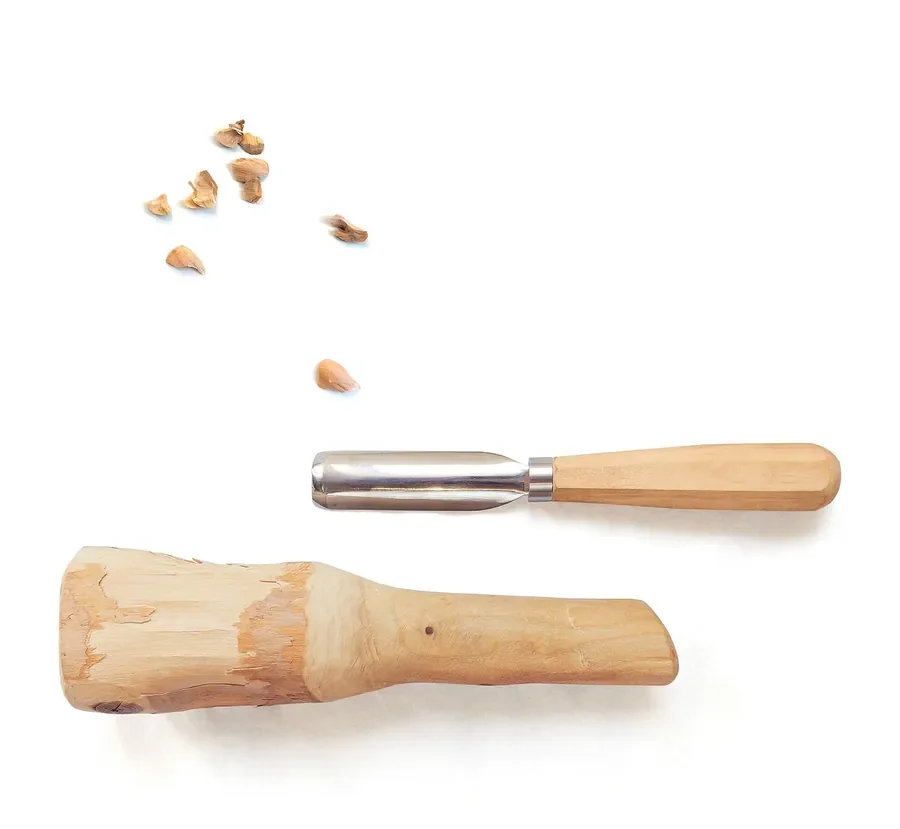 Carving gouge lying beside a carved piece of wood and loose wood shavings Carving gouge lying beside a carved piece of wood and loose wood shavings