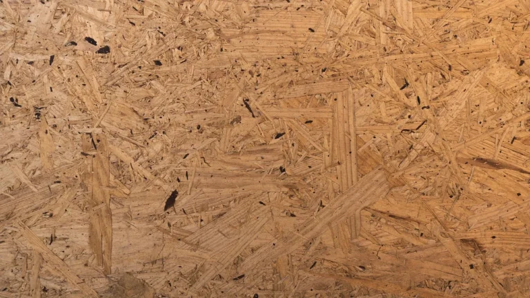 Close-up of an OSB oriented strand board panel surface showing the compressed wood strand layers