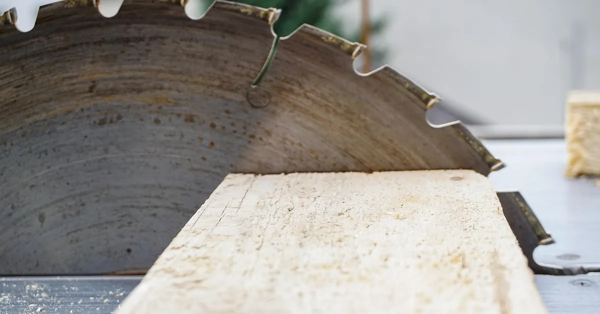 Circular saw blade with large alternating teeth ripping through a wood board on a table saw