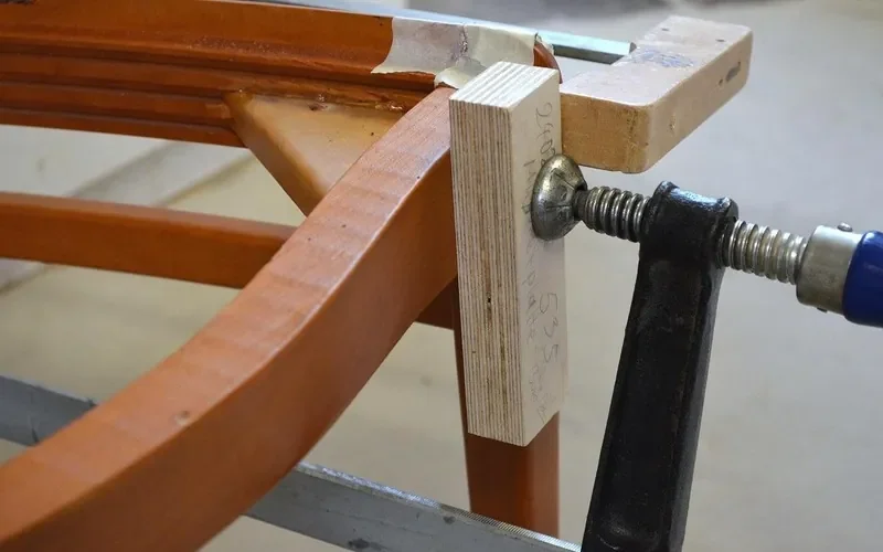 Bar clamp with a scrap block protecting a wooden frame joint