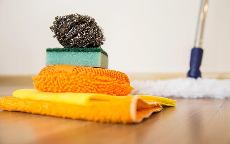 Microfiber cloths, a scrub pad and a mop head arranged on a wood floor Microfiber cloths, a scrub pad and a mop head arranged on a wood floor
