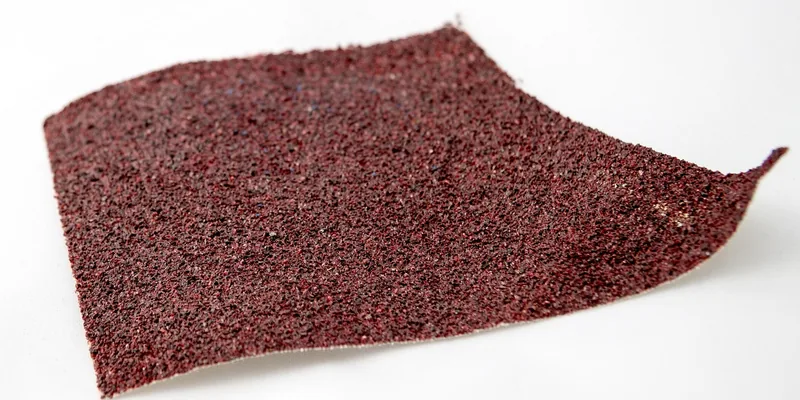 close-up of a coarse-grit sandpaper sheet used to strip varnish from wood