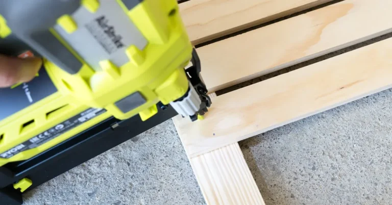 pneumatic finish nailer driving a nail into pine trim board