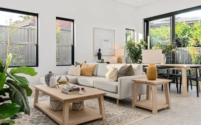 Modern living room with wood-framed tables and glass elements near a sliding glass door Modern living room with wood-framed tables and glass elements near a sliding glass door