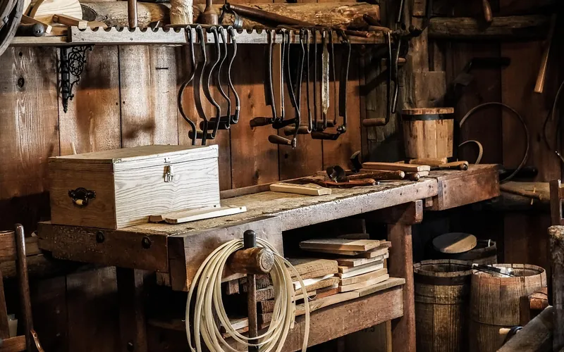 Old hand-tool workshop bench beside wooden barrels