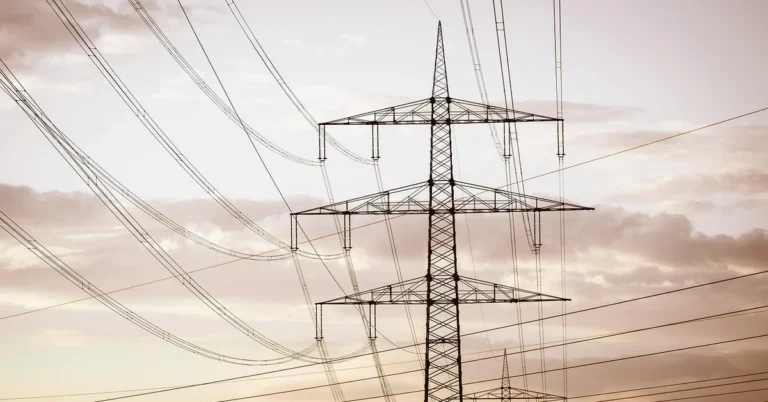 high-voltage electrical transmission lines against the sky, representing the lethal current risk of DIY wood burning
