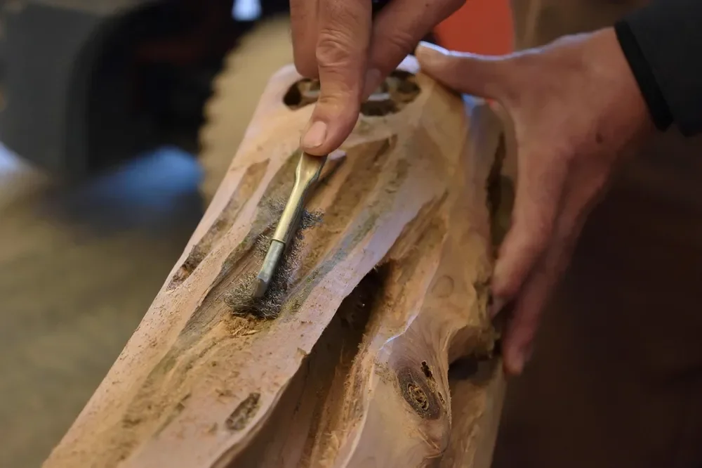 Hands working inside a hollowed channel cut into a solid timber