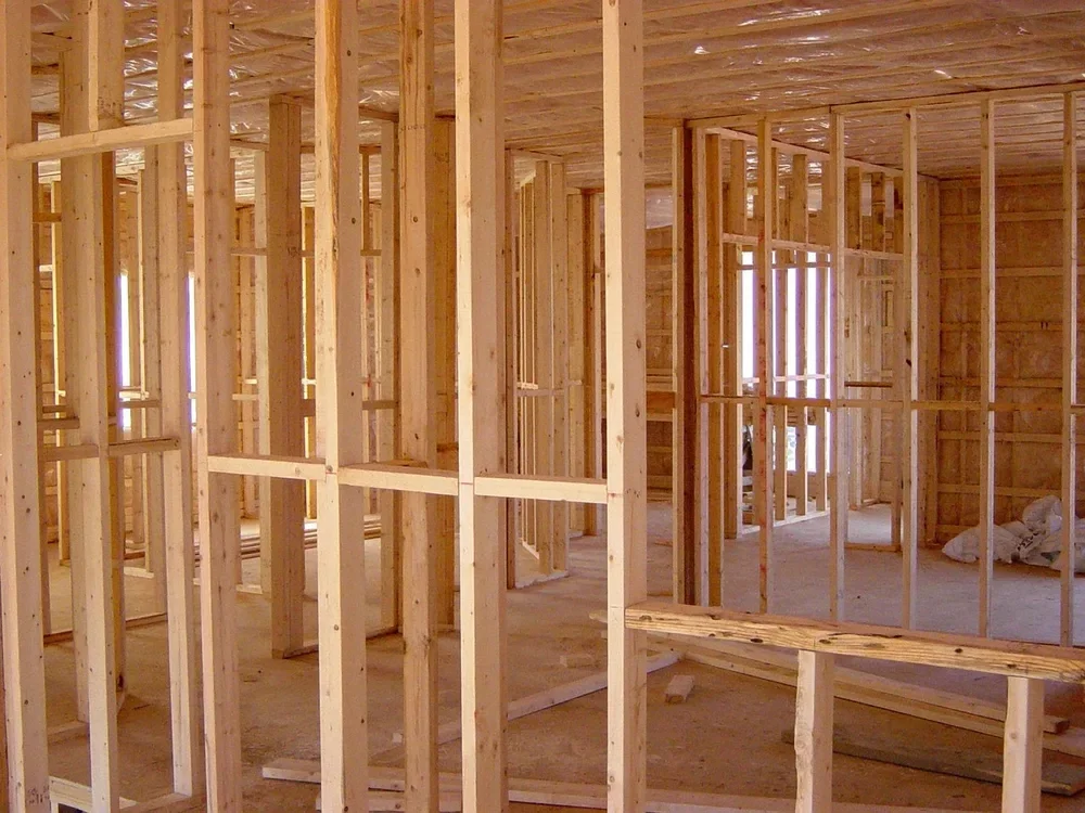 Wood-framed house under construction showing framing lumber and panel demand