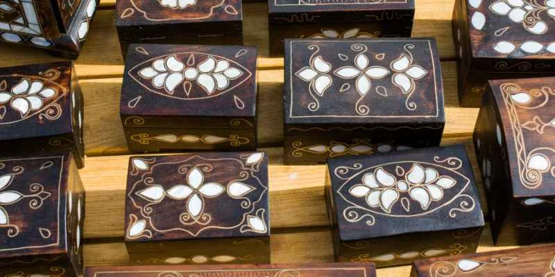 Dark wooden boxes with light floral inlay motifs set flush into the lid