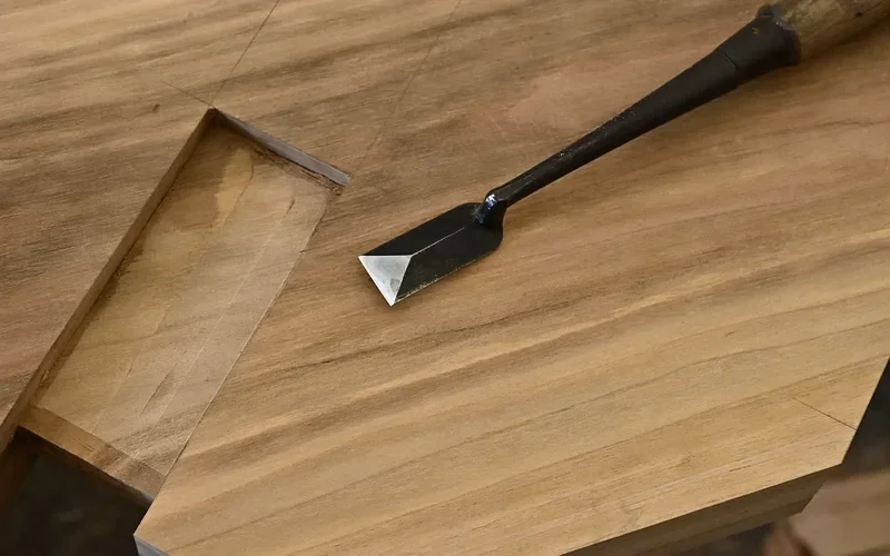 Japanese chisel resting on a freshly cut recess in a timber joint
