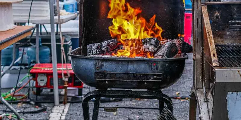 kettle grill with hardwood logs actively burning down into a coal bed kettle grill with hardwood logs actively burning down into a coal bed