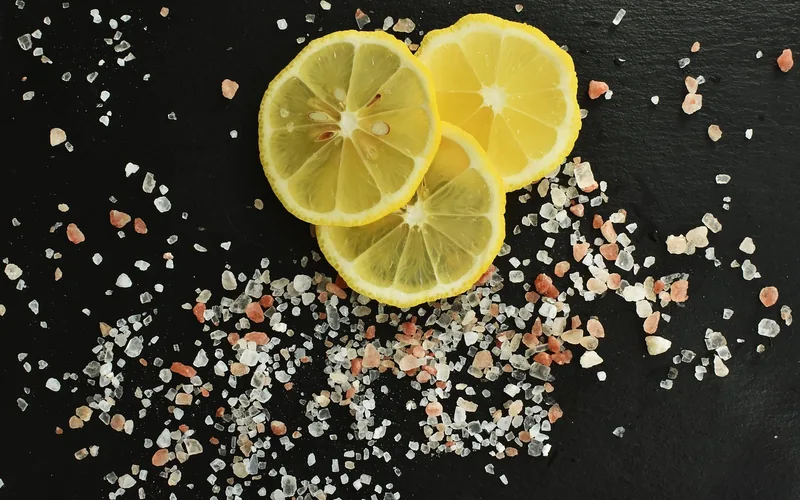 Lemon slices and coarse salt used to scrub stains and odors from a wooden cutting board