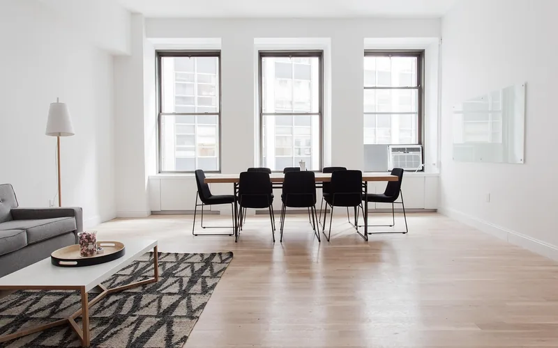 Light wood floor and wood dining table with black chairs in a bright room