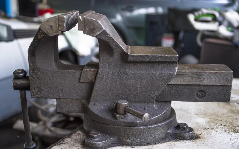 a metal bench vise clamping a workpiece steady in a workshop a metal bench vise clamping a workpiece steady in a workshop
