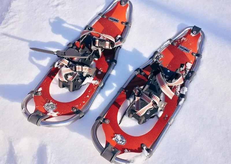 Pair of modern aluminum-frame snowshoes with plastic decking lying on snow