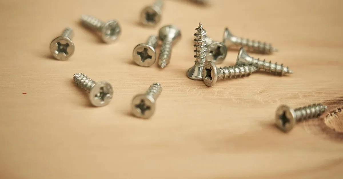 Wood screws scattered on a light wood surface