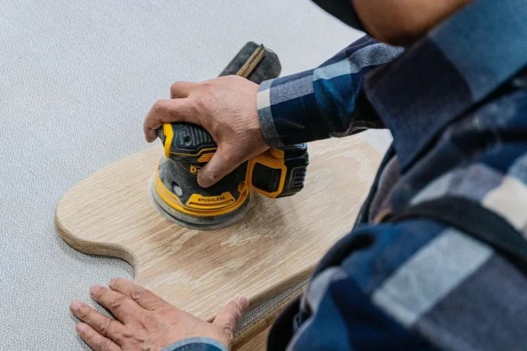 Random-orbit sander smoothing a wood panel during tabletop sanding