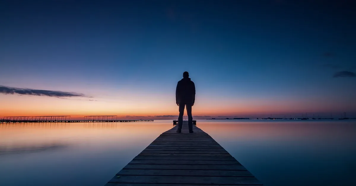 wooden deck extending over a calm pond at dusk