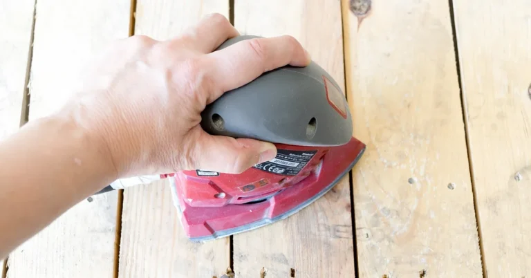 hand sanding a wood table top with an orbital sander after flattening