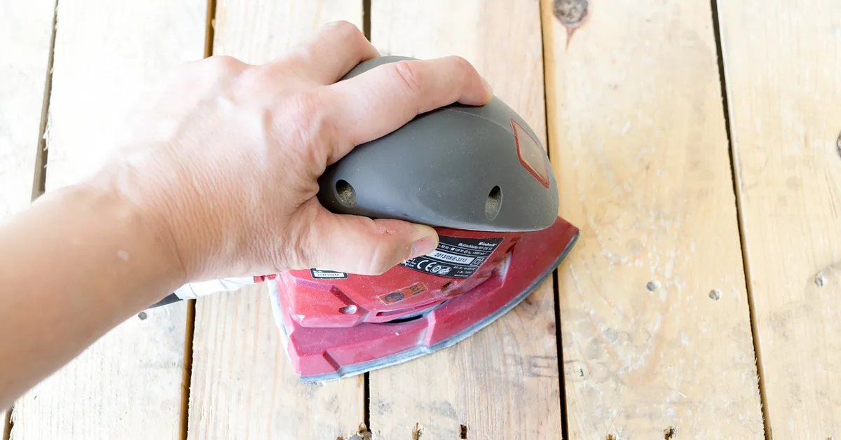 hand sanding a wood table top with an orbital sander after flattening