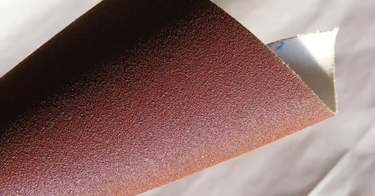 Close-up of fine-grit sandpaper sheet, the abrasive compared to 0000 steel wool