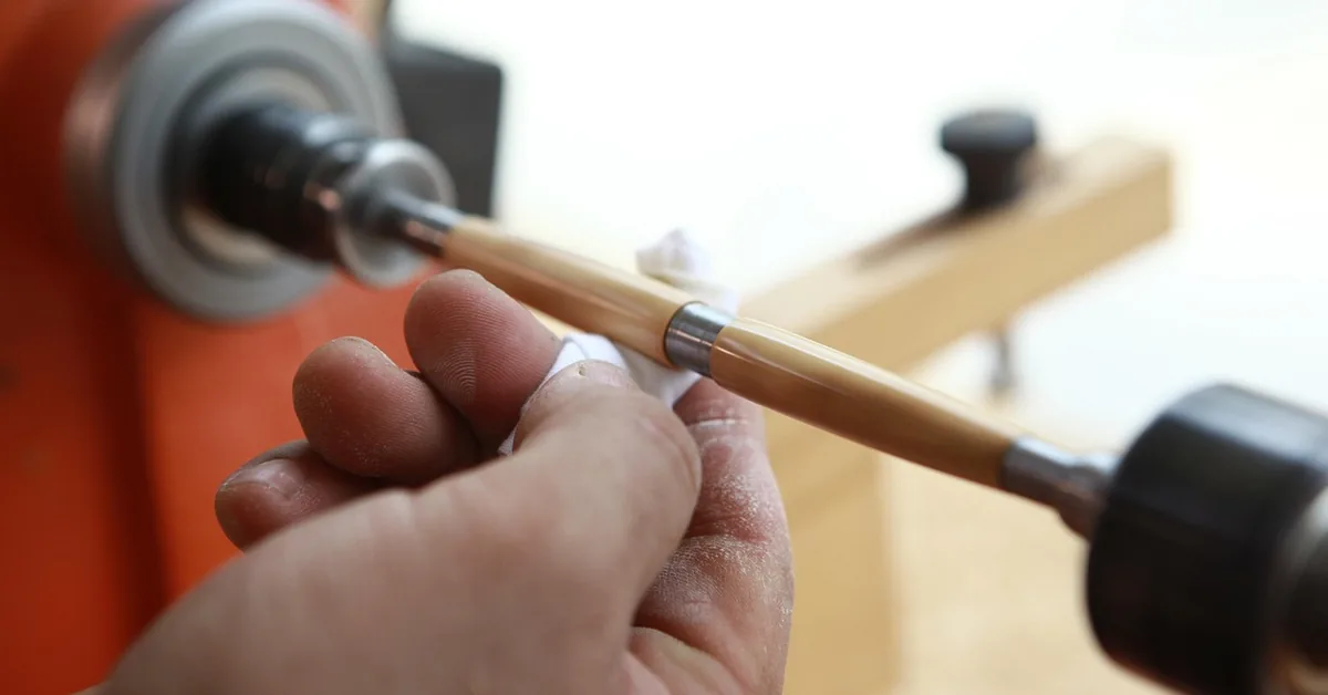 carpenter turning a wooden dowel on a lathe in a workshop