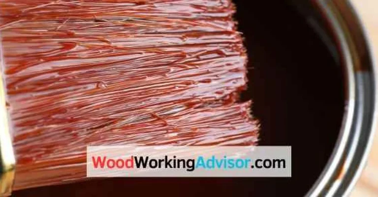Paintbrush dipped in dark stain used for staining over painted wood