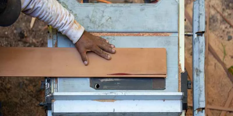 Hand guiding a board through a table saw rip cut