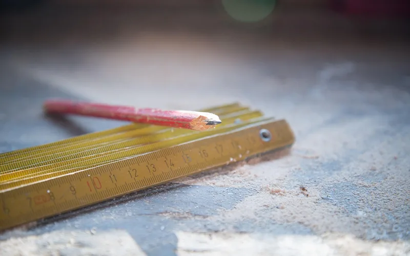 Carpenter using precise measurement tools before a table saw cut to prevent alignment errors