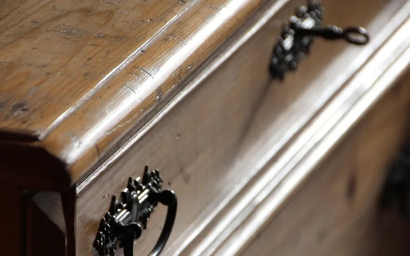 close-up of an antique wooden dresser drawer front with a warm brown waxed finish
