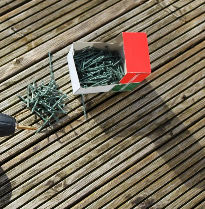 Box of coated deck screws lying on weathered decking boards